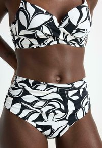 Sort og hvid bikini med et blomstermønster. Materialet ser glat ud med en struktureret design. Toppen har en samlede buste med brede stropper.