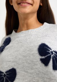 Pulover gri deschis cu tricotaj texturat, având modele de funde pufoase bleumarin. Guler cu dungi și țesătură moale. Vedere de aproape.