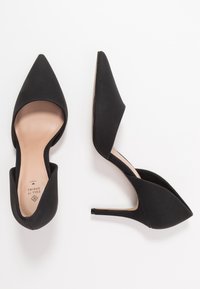 Scarpe con tacco alto nere, punta affusolata, tomaia testurizzata e design elegante e curvo, con tacco a stiletto e soletta color nude.