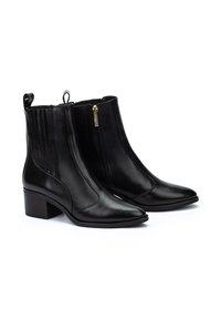 Botas negras de cuero hasta el tobillo con punta afilada, cremallera lateral y tacón bajo en bloque. Presentan acanalados verticales en los lados.
