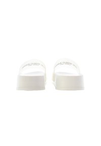 White slide sandals with a smooth, matte finish. Open toe, wide straps, and a low wedge sole with subtle texture on the surface.