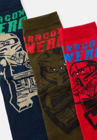 Tri par socka: jedan tamnoplavi s grafičkim dizajnom koji prikazuje lik, jedan maslinasto zeleni s tamnim dizajnom i jedan crveni s plavim akcentima.