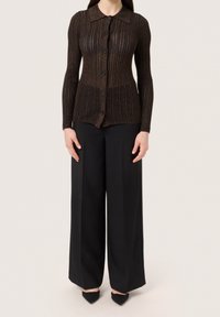 Brun ribbad stickad cardigan med långa ärmar, knappstängning och krage. Kombinerad med svarta vida byxor och spetsiga svarta klackar.