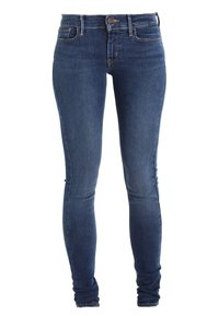 Jeans de mezclilla azul ajustados con una cintura alta, que presentan un cierre frontal con botón y un diseño clásico de cinco bolsillos, mostrados en posición vertical.