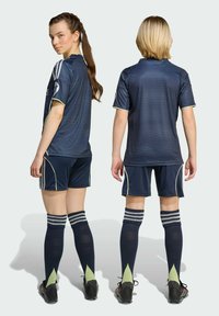 Marinsportuniform bestående av en kortärmad tröja och shorts med ljusgröna detaljer, kompletterat med knästrumpor och fotbollsskor.