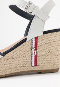 Vita läder espadrille-klack med en flätad jute-häl. Accentuerad med marinblått tyg och ett röd-vit-blått rand med en detaljerad silverlogotyp.