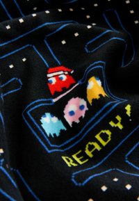 Plüss takaró fekete alapon, pixelizált Pac-Man mintával, színes szellemekkel és a "READY!" felirattal élénk sárgában.