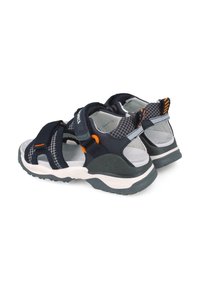 Sandalias azul marino con correas ajustables, una entresuela blanca y una suela gris texturizada. Presenta detalles de patrón de rejilla y detalles en naranja.