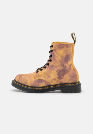 Geel en paars tie-dye veterboot met zwarte zool en gele stiksels, voorzien van een trek-lus aan de achterkant.