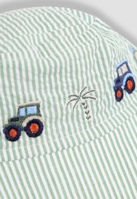 Striped green and white bucket hat with embroidered tractors and a palm tree, featuring a soft cotton texture and a round, structured shape.