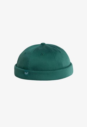 Dark green wool beanie hat with a folded brim and stitched eyelets, featuring a small fabric tag on the side.