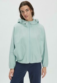 Hellblaues zip-up Hoodie aus weichem Material, mit Kapuze, großen Fronttaschen und gerippten Bündchen. Lässiger, oversized Schnitt mit Nahtdetails.