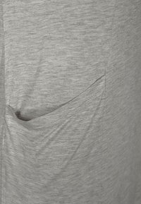 Tessuto grigio con una sottile texture melange, caratterizzato da una tasca curva sul lato, bordi cuciti e cuciture minime.