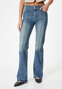 Blå flaxade jeans med hög midja, som har två framfickor, dubbel kn�äppning och fransad nederkant. Slät, något urblekt denimtextur.