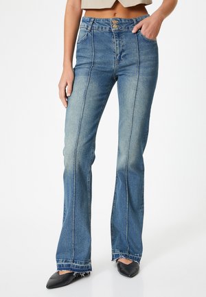 Jeans acampanados azules con cintura alta, que cuentan con dos bolsillos frontales, cierre de doble botón y un dobladillo deshilachado. Textura de denim suave y ligeramente descolorido.