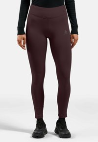 Bordeaux leggings gemaakt van een gladde, rekbare stof. Hoog tailleband en subtiel logo-detail op de heup. Gestyleerd met zwarte schoenen.