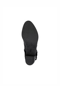 Semelle de chaussure noire avec un motif texturé comportant des formes géométriques. Zone des orteils lisse et talon légèrement surélevé pour la stabilité.