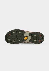 Semelle de chaussure d'extérieur avec une bande de roulement noire, des rainures profondes, des accents rouges et blancs, et un logo Vibram jaune au centre.