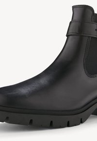 Stivale alla caviglia in pelle nera con finitura liscia, pannelli elasticizzati ai lati, punta arrotondata e suola in gomma spessa con motivi di battistrada profondi.