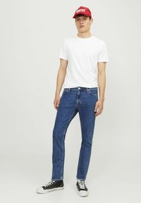 Tricou alb cu guler rotund, blugi droit de culoare albastră, adidași negri cu gleznă înaltă, șapcă de baseball roșie, croială casual, material simplu, denim albastru mediu.