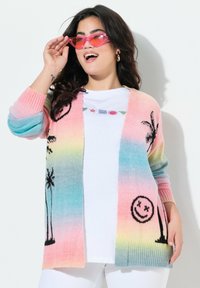 Gebreide cardigan met een verloop van roze, blauw en geel; zwarte palmboom- en glimlachgezichtpatronen; open voorkant en ribgebreide manchetten.