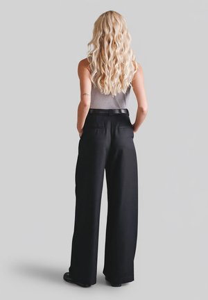 Czarne, szerokie spodnie z wysokim stanem o gładkiej fakturze i tylnych kieszeniach, zestawione z dopasowanym szarym topem na ramiączkach.
