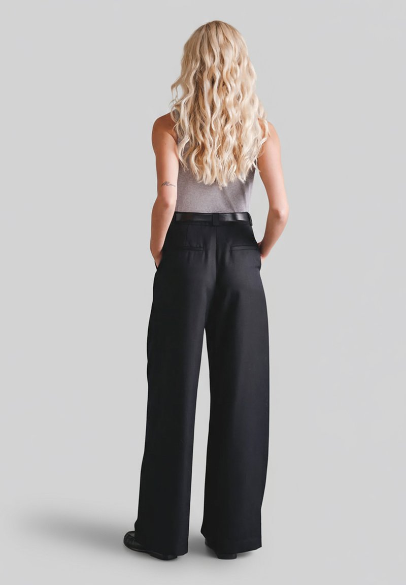 Czarne, szerokie spodnie z wysokim stanem o gładkiej fakturze i tylnych kieszeniach, zestawione z dopasowanym szarym topem na ramiączkach.