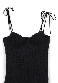 Schwarzes ärmelloses Kleid aus Ösenstoff, mit Herz-Ausschnitt, strukturiertem Bustier und gebundenen Trägern auf einem weißen Hintergrund.