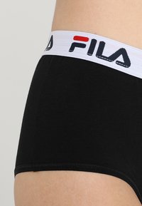 Fekete pamut boxer alsónadrág fehér gumírozott derékkal, amelyen fekete és piros FILA logó található. Sima textúra, testhezálló dizájn.