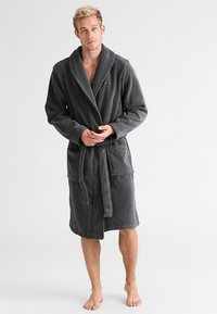 Graue Frottee-Bademantel mit Schalkragen, taillierten Gürtel und zwei Fronttaschen. Weiche Textur und knielanges Design.
