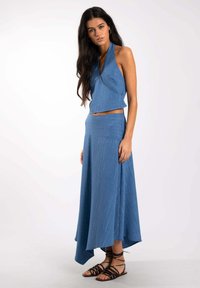 Conjunto de dos piezas en una tela de color azul claro con un patrón texturizado. Top de halter con un diseño corto y una falda larga fluida con un dobladillo asimétrico.
