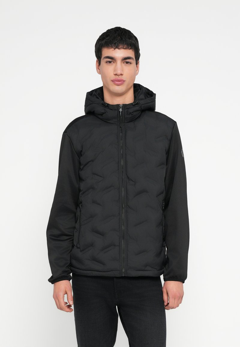 Svart dunjakke med quiltet design, har glidelåslukking og justerbar hette. Ermene er laget av et glatt materiale.