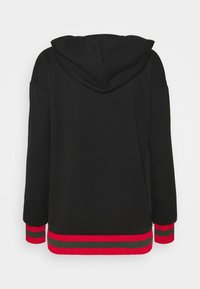 Sudadera negra con una capucha grande, que presenta acentos de rayas rojas y verdes en los puños y el dobladillo. Tejido suave con un corte relajado.