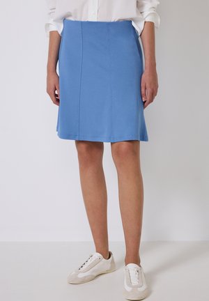 Blauwe jurk A-lijn rok met een gladde textuur, knielang, en subtiele naden, gecombineerd met witte sneakers en een overhemd met knopen.