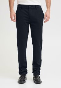 Pantaloni navy in misto cotone con chiusura a bottone, design a gamba dritta e leggero elasticizzato, abbinati a scarpe eleganti nere.