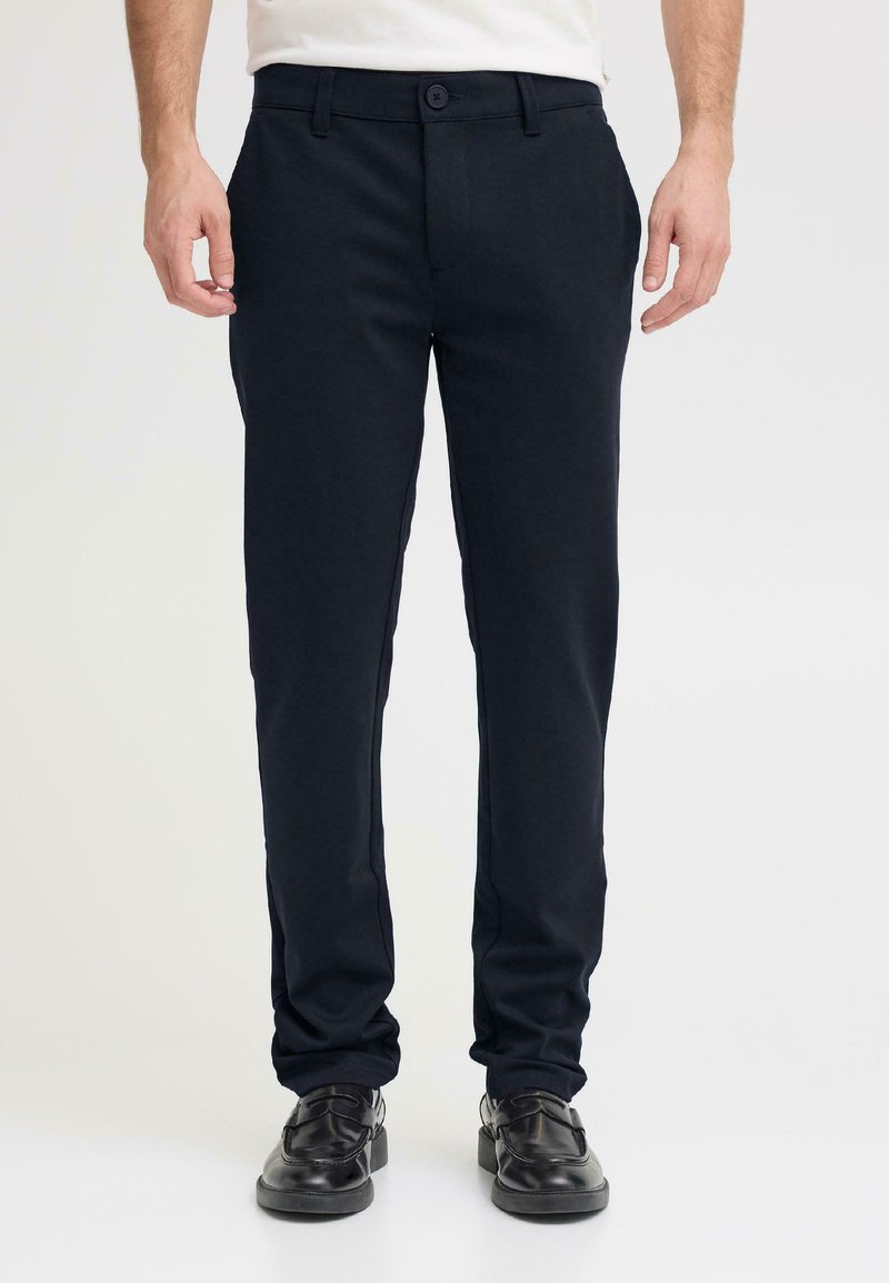 Pantaloni navy in misto cotone con chiusura a bottone, design a gamba dritta e leggero elasticizzato, abbinati a scarpe eleganti nere.
