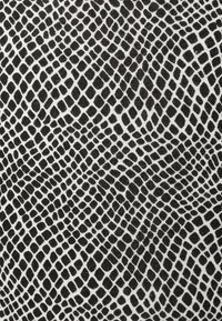 Monokromt tyg med en strukturerad mönstring av sammanlänkade svarta och vita former som efterliknar ett reptilhudsmönster.