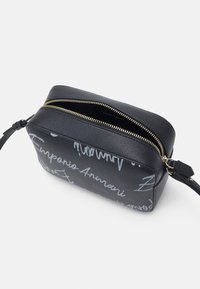 Black leather wristlet bag with gold zipper and white cursive writing of the brand name "Emporio Armani" on its surface.