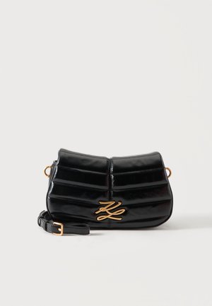 Borsa a tracolla in pelle nera con design trapuntato, logo color oro sul davanti e tracolla regolabile con fibbia dorata su sfondo semplice.