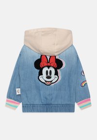 Denimjacka med beige huva, med en broderad design av Minnie Mouse på baksidan. Inkluderar färgglada randiga ärmslut och regnbågsdetaljer.