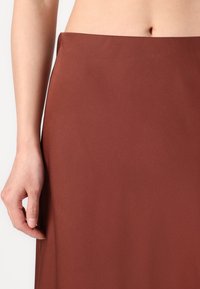 Hnědá, hladká sukně s vysokým pasem, s rovnou siluetou a bez viditelných vzorů nebo kovových detailů.