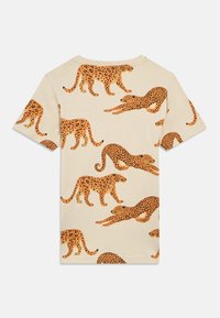 Trumpomis rankovėmis leopardų rašto marškinėliai iš smėlio spalvos medvilnės, su keliais oranžiniais leopardais įvairiose pozose, juodais taškeliais pabrėžiantiais raštą.