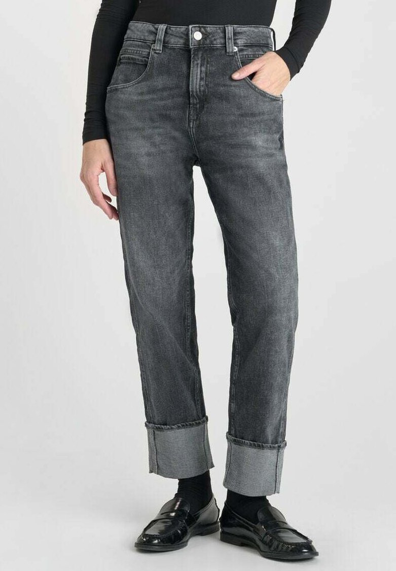 Jean en denim noir avec taille haute, jambe fuselée et ourlets retroussés. Présente des poches avant et une fermeture à bouton. Finition en tissu texturé.