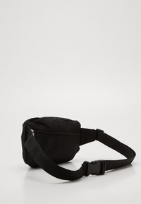 Sac banane en tissu noir avec un compartiment zippé, une sangle réglable et une boucle en plastique durable. Forme arrondie, texture lisse.