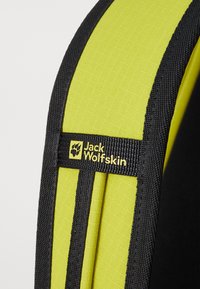 Geel en zwart gevoerd hengsel met textuurstof, versterkte randen en een geel logo-etiket voor Jack Wolfskin.