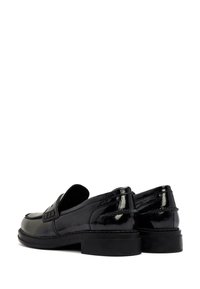 Mocasines de charol negro con un bajo tacón bloque, que presentan una banda texturizada en la parte superior y un acabado suave y brillante.