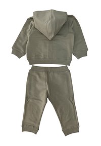 Felpa con cappuccio in cotone verde oliva con polsini e orlo a costine, abbinata a pantaloni coordinati con vita elasticizzata e gambe affusolate.