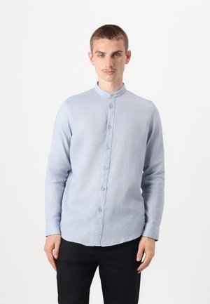 Light blue, long-sleeved shirt with a mandarin collar, featuring a button-down front, made from a textured fabric. Styled with black trousers.