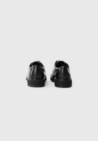 Schwarze Lederschuhe mit runder Zehenpartie, flachem Design und strukturiertem Laufsohle. Glatte Oberfläche mit minimalen Nähdetails.