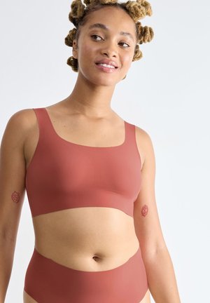 Bralette couleur rouille et culotte taille haute assortie, fabriquées dans un tissu doux, avec des bretelles larges et un design minimaliste.